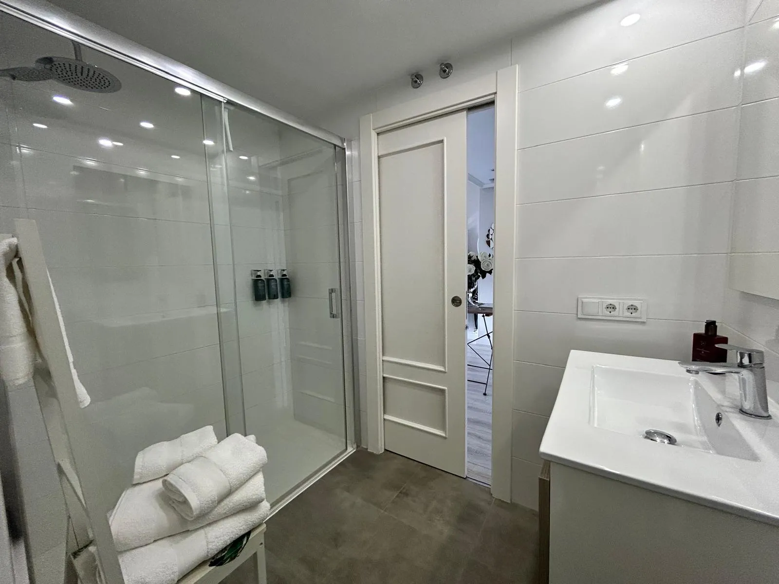 Baño con ducha de mampara, lavabo y toallas