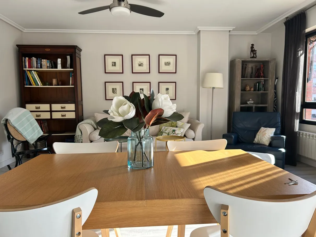 Mesa de comedor con flores y el salón al fondo