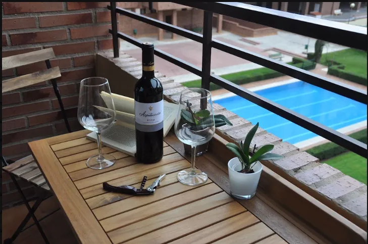 Terraza con mesa, copas y vino de Rioja, con vistas a la piscina